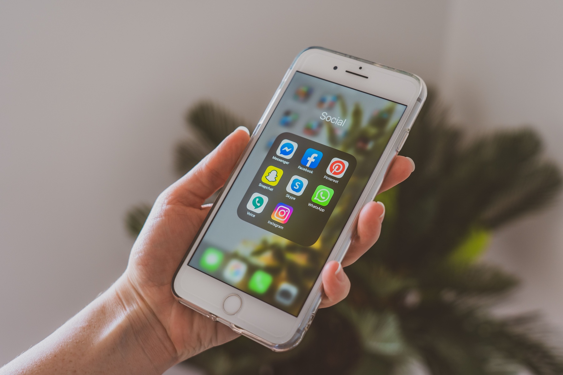 pexels-castorlystock-4114787 A hand holding a mobile phone with app icons in view.